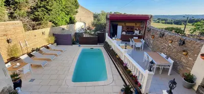 an outdoor swimming pool with chairs and a table at La maison millesime in La Caunette
