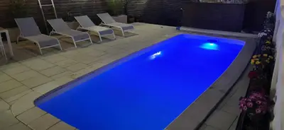 a blue swimming pool in a yard with chairs at La maison millesime in La Caunette