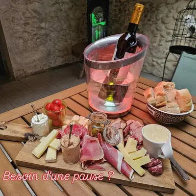 a wooden table with a bottle of wine and cheese at Love Room CHARME et PLAISIRS in Mazamet