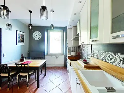 a kitchen with a table and chairs and a clock on the wall at Love Room CHARME et PLAISIRS in Mazamet