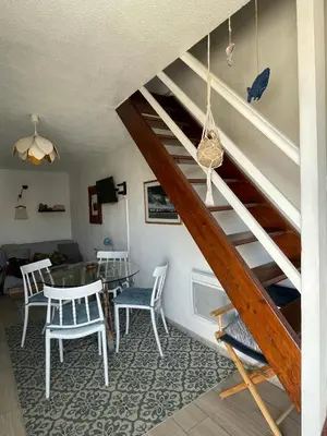 a living room with a staircase with a table and chairs at Duplex plage des chalets Gruissan plage in Gruissan