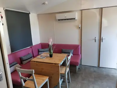 a living room with a pink couch and a table at ZEN Mobil Home Occitanie 6P Tout confort & Climatisation in Port-la-Nouvelle
