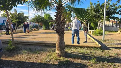 a man walking down a sidewalk next to a palm tree at ZEN Mobil Home Occitanie 6P Tout confort & Climatisation in Port-la-Nouvelle