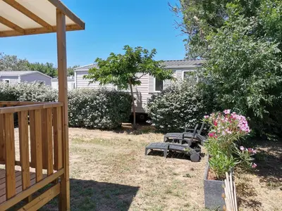 a yard with a bench and flowers and a house at ZEN Mobil Home Occitanie 6P Tout confort & Climatisation in Port-la-Nouvelle