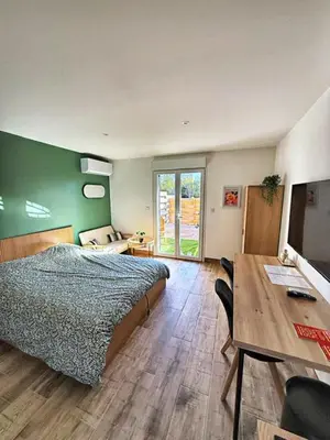 a bedroom with a bed and a desk and a table at Studio à l'écurie 2 in Narbonne