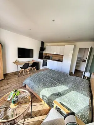 a bedroom with a bed and a kitchen with a table at Studio à l'écurie 2 in Narbonne