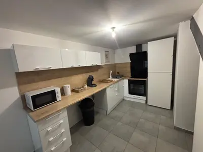 a kitchen with white cabinets and a counter with a microwave at Maison cosy et chaleureuse in Pont-de-Larn