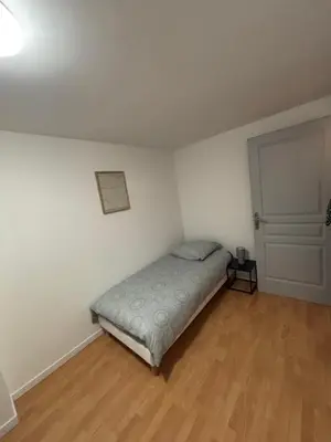 a small bedroom with a bed and a wooden floor at Maison cosy et chaleureuse in Pont-de-Larn