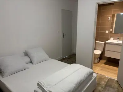 a bedroom with a white bed and a bathroom at La Parenthèse Carcassonnaise in Carcassonne