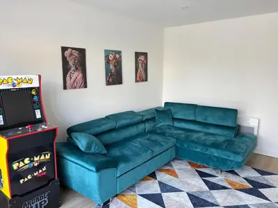a living room with a green couch and a video game at La Parenthèse Carcassonnaise in Carcassonne