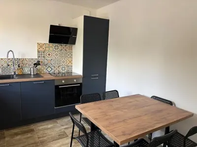 a kitchen with a wooden table and some chairs at La Parenthèse Carcassonnaise in Carcassonne