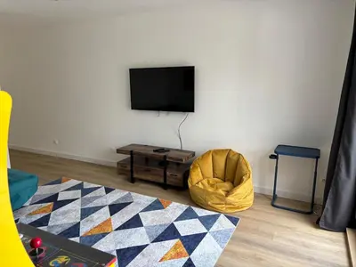 a living room with a flat screen tv and a chair at La Parenthèse Carcassonnaise in Carcassonne