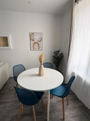 a dining room with a white table and blue chairs at Le Soult l Rénové l Stationnement facile & gratuit in Mazamet