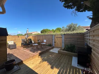 a patio with a table and chairs on a wooden deck at Gîte de la Trémiére in Salles-d'Aude