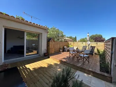 a patio with a table and chairs on a deck at Gîte de la Trémiére in Salles-d'Aude