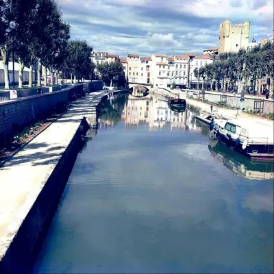 a river in a city with a boat in it at Gîte de la Trémiére in Salles-d'Aude