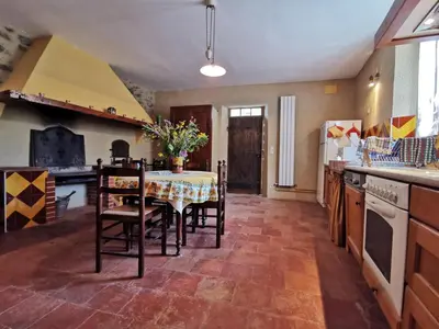 a kitchen with a table and chairs and a kitchen with a stove at La maison du berger in Cassagnes