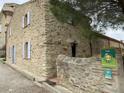 a stone building with a sign in front of it at La maison du berger in Cassagnes