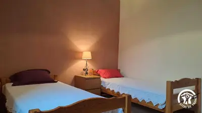 a bedroom with two beds and a lamp on the wall at L'esquirou in Castres