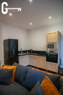 a living room with a couch and a kitchen at Elegant T2 avec terrasse Coeur de Castelnaudary Gare in Castelnaudary