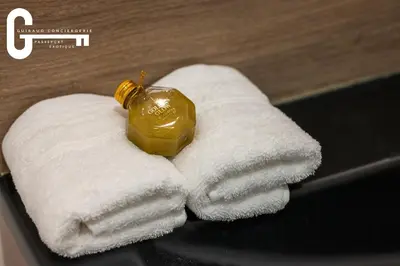 a pile of white towels with a bottle on top at Elegant T2 avec terrasse Coeur de Castelnaudary Gare in Castelnaudary