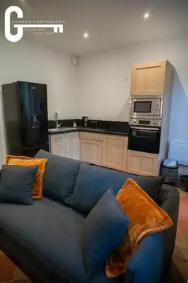 a living room with a blue couch and a kitchen at Elegant T2 avec terrasse Coeur de Castelnaudary Gare in Castelnaudary