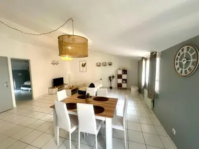 a dining room with a table and chairs and a clock at Cosy Appartement 45 m2 en cœur de ville, proche gare in Narbonne