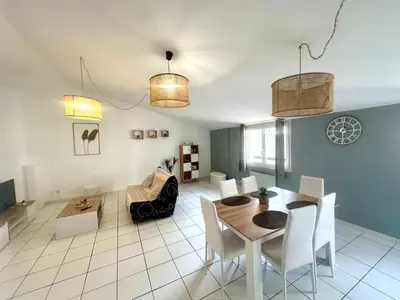 a dining room and living room with a table and chairs at Cosy Appartement 45 m2 en cœur de ville, proche gare in Narbonne