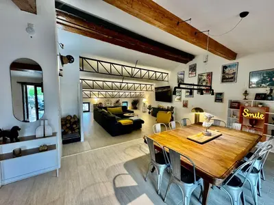 a dining room and living room with a wooden table at Grande maison de charme près de Carcassonne avec terrasse et jardin in Palaja