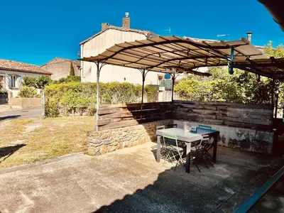 a picnic table under an umbrella in a backyard at Grande maison de charme près de Carcassonne avec terrasse et jardin in Palaja