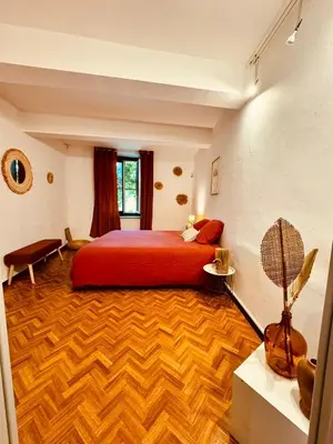 a bedroom with a red bed and a wooden floor at Grande maison de charme près de Carcassonne avec terrasse et jardin in Palaja