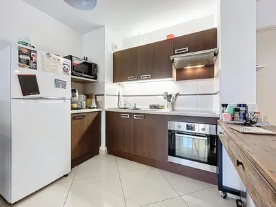 a kitchen with wooden cabinets and a white refrigerator at Le Pech - 6personnes - proche des plages - Clim in Gruissan