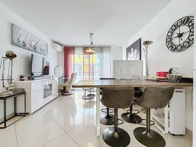 a kitchen with a dining table and a clock on the wall at Le Pech - 6personnes - proche des plages - Clim in Gruissan