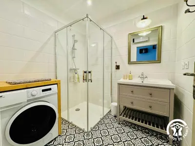 a bathroom with a shower and a sink and a washing machine at Gite de l'avenue in Sigean