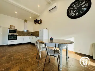 a kitchen with a table and a clock on the wall at Gite de l'avenue in Sigean