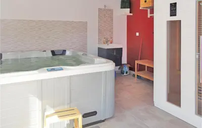 a bathroom with a tub with a chair in it at Nice Home In Narbonne With Sauna in Narbonne
