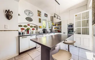 a large kitchen with white cabinets and a large island at Awesome Home In Capendu in Capendu