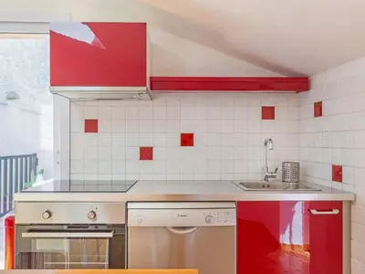 a kitchen with red cabinets and a sink at Opuntia Teouliero location en Méditerranée in Escales