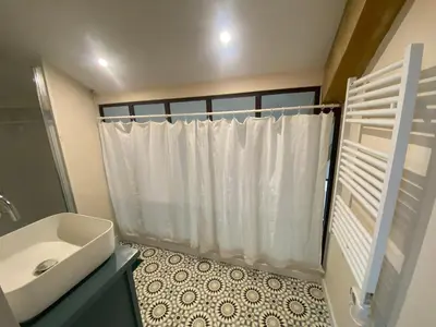 a bathroom with a white shower curtain and a sink at Chambres d'hôtes -L'Atelier du Presbytère