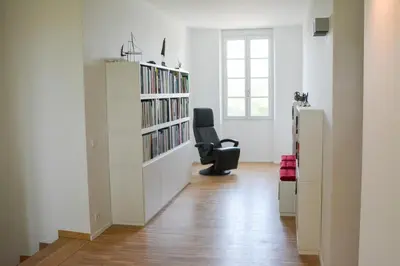 a room with a chair and a book shelf with books at Le domaine de rigou in Lasbordes