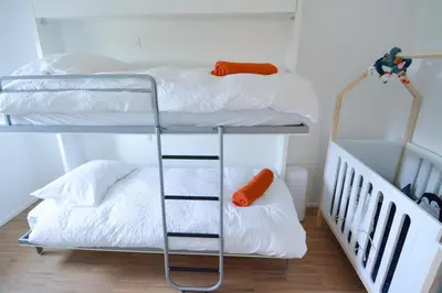 two bunk beds with white sheets and an orange pillow at Le domaine de rigou in Lasbordes