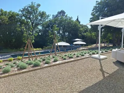 a garden with plants and umbrellas next to a pool at Le domaine de rigou in Lasbordes