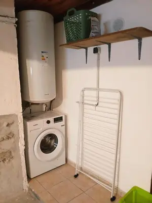 a laundry room with a washing machine and a shelf at Maison Au Phil de Lau in Raissac-dʼAude
