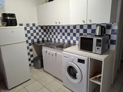 a kitchen with a washing machine and a microwave at Appartement T2 entre mer et lac in Port-la-Nouvelle
