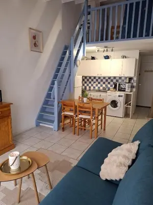 a living room with a table and a staircase at Appartement T2 entre mer et lac in Port-la-Nouvelle