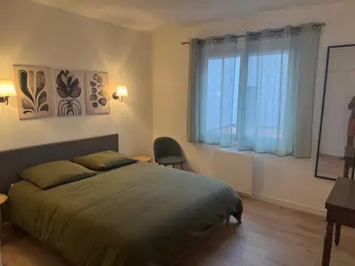 a bedroom with a bed and a desk and two windows at Appartement centre ville Sigean in Sigean