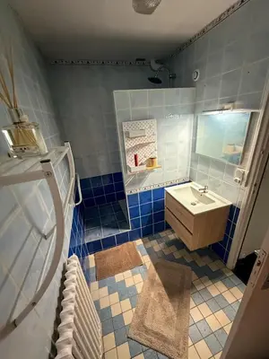 a blue tiled bathroom with a sink and a shower at Les Fleurs de la Cité - T3 Parking privé et Terrasse Jardin Privé in Carcassonne