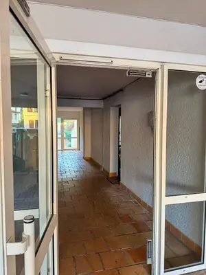 an empty hallway of a building with glass doors at Les Fleurs de la Cité - T3 Parking privé et Terrasse Jardin Privé in Carcassonne
