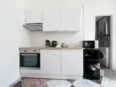 a white kitchen with a stove and a microwave at Charmant T2 Narbonne centre in Narbonne