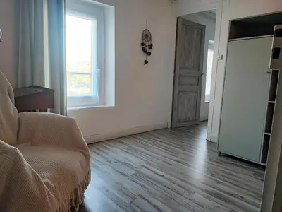 an empty living room with a chair and a window at Chez Christine et Fred in Villedaigne